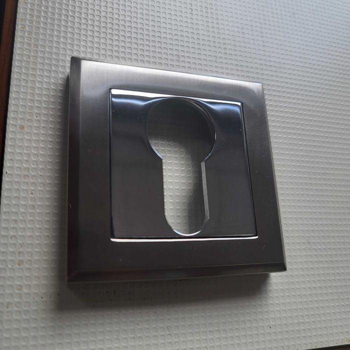 Nowa, elegancka klamka drzwiowa na kwadratowym szyldzie.