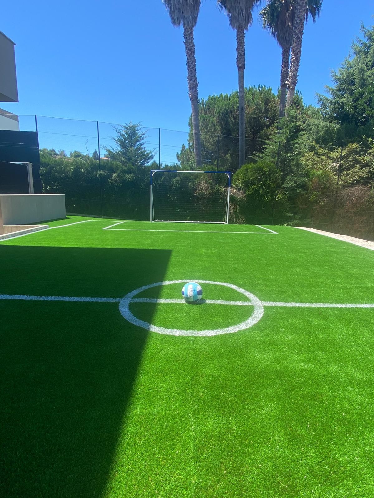 Espaço exterior com piscina e campo de jogos.