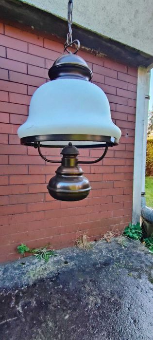 Lampa wisząca z szklanym kloszem i metalowymi elementami wykończenia.