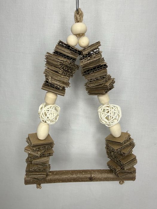 Mała huśtawka dla ptaków z tekturą i kulami wiklinowymi.