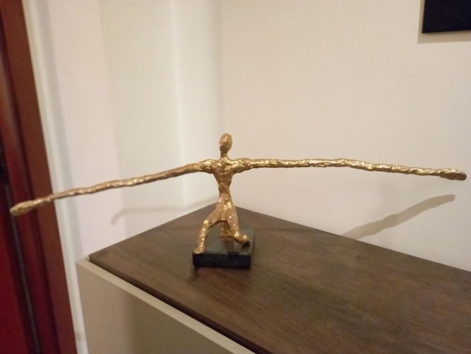 Homem de braços abertos com base em granito