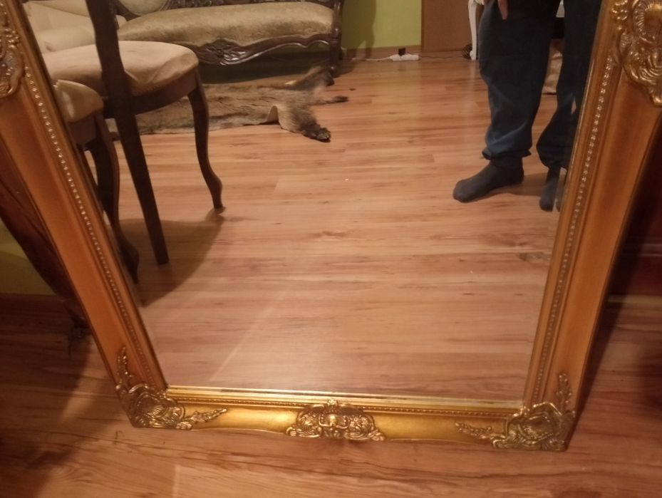 Duże lustro fazowane zdobione prostokątne w złotej ramie.