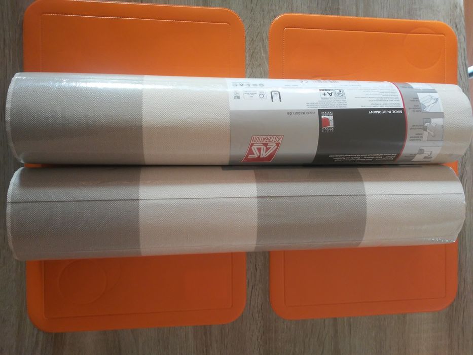 Dwie rolki pięknej tapety w pasy na flizelinie.