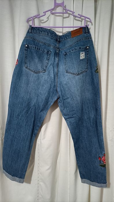 Calças de ganga para senhora com padrões de rosas vermelhas.