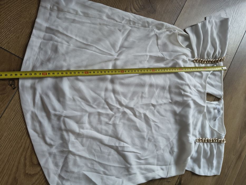 Elegancka ecru bluzka ze złotymi łańcuszkami falbany na ramionach