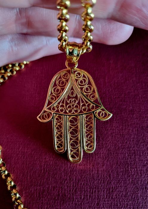 Colar comprido dourado, em aço, com a mão de Fátima em filigrana..