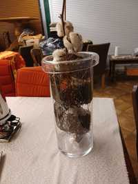 Szklany wazon z ozdobnym wkładem i drobnymi lampeczkami.