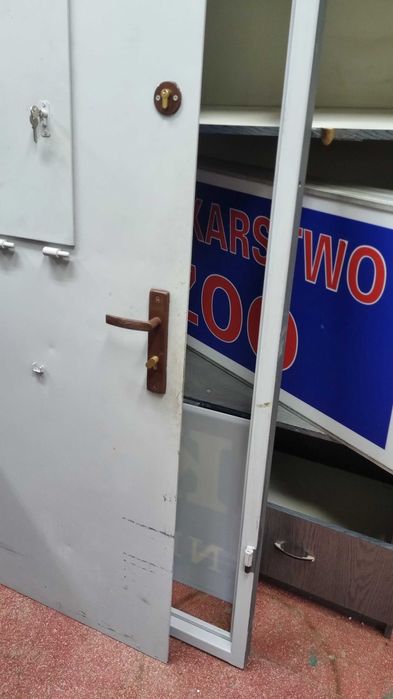 Drzwi stalowe antywłamaniowe z ramą i okienkiem podajnikowym.