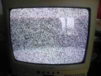 Televisão antiga a cores a funcionar, com comando e suporte de parede