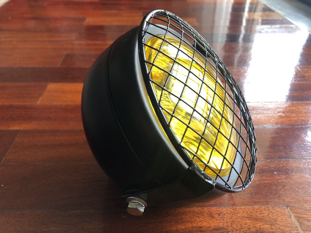 Farol frontal amarelo com grelha metálica dois apoios cafe racer