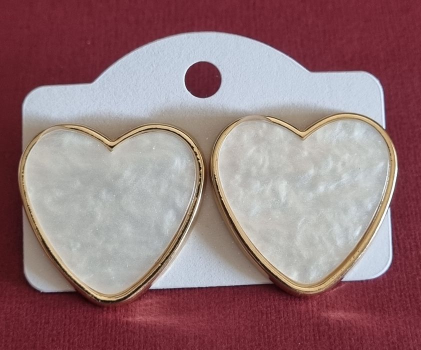 Brincos, de picos, com forma de coração branco delineado a dourado.