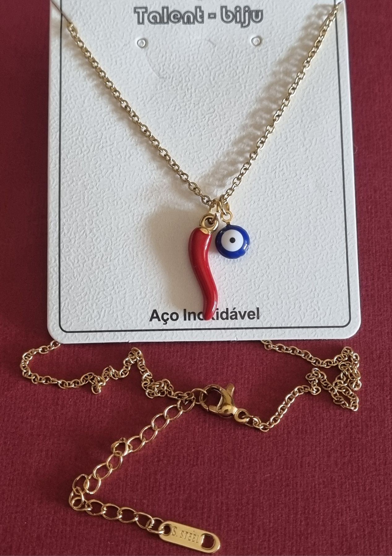 Colar dourado, em aço, com pimentinha e olho grego. Tem extensor