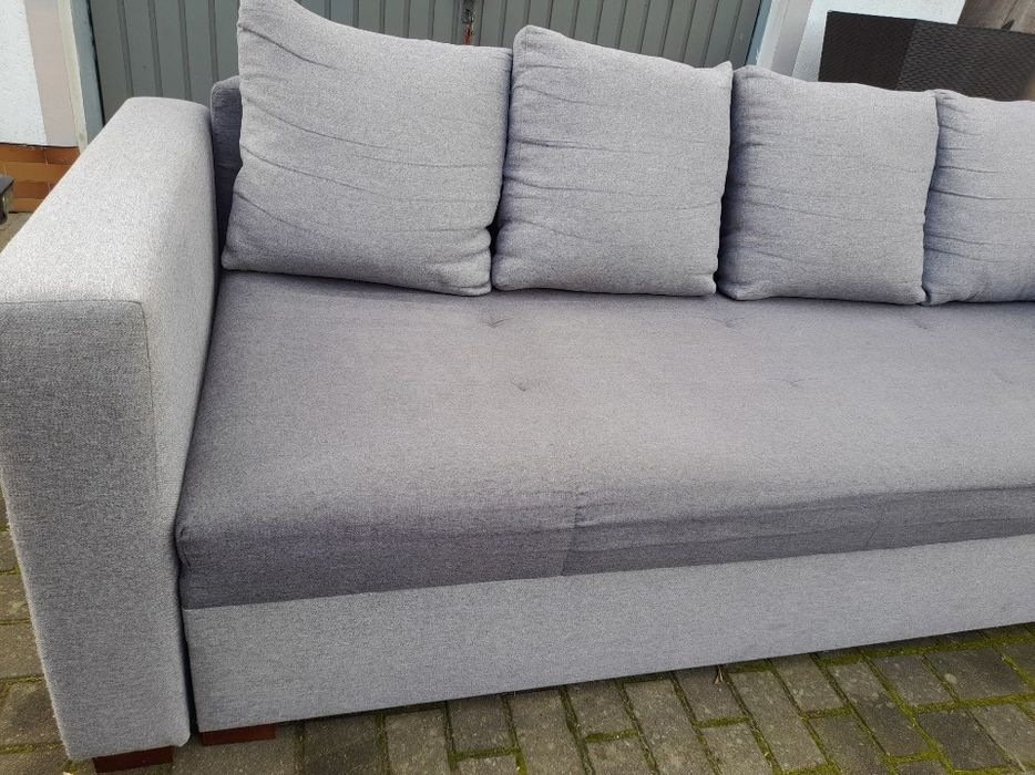 Szara kanapa z funkcją spania i dwoma pufami