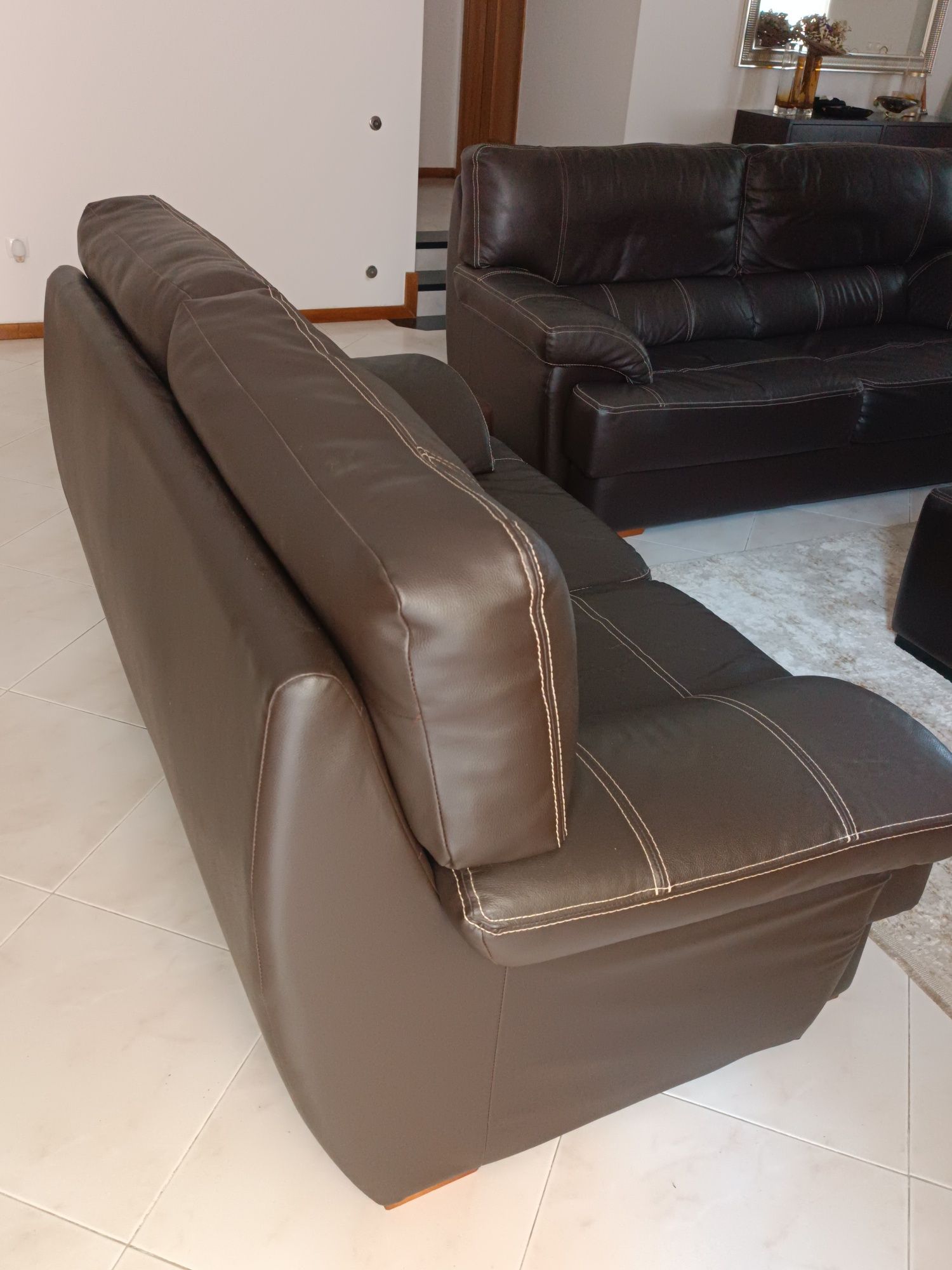 Vendo sofás em pele cor castanho.