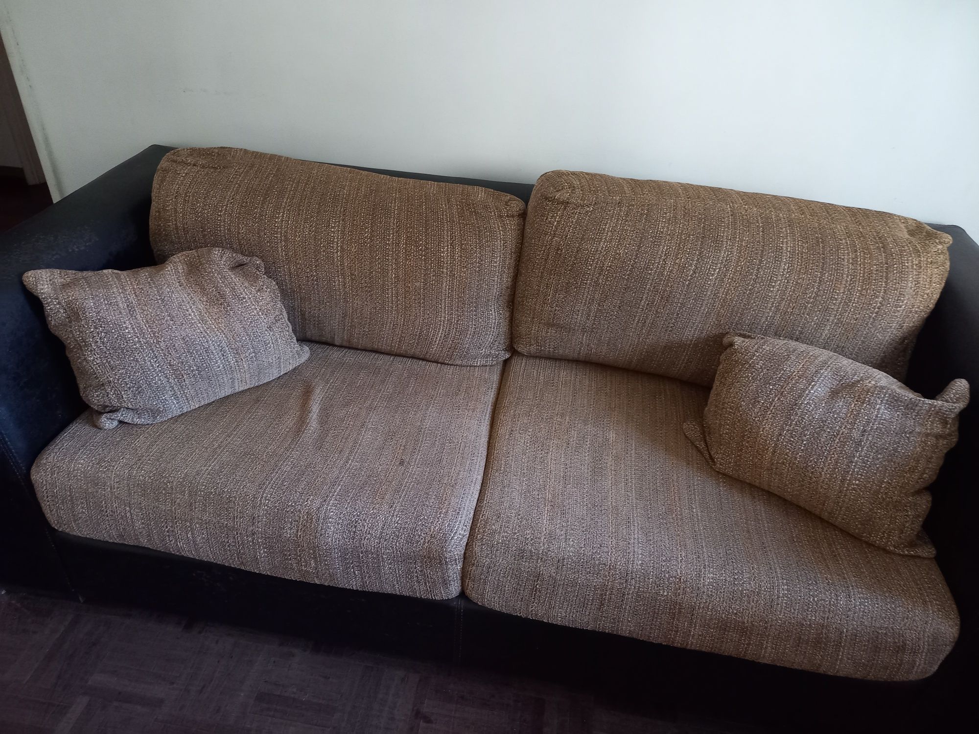 Sofa em pele castanho escuro com almofadas beje e castanhas