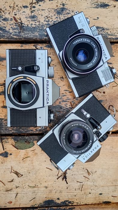 Trzy aparaty Praktica z obiektywami.