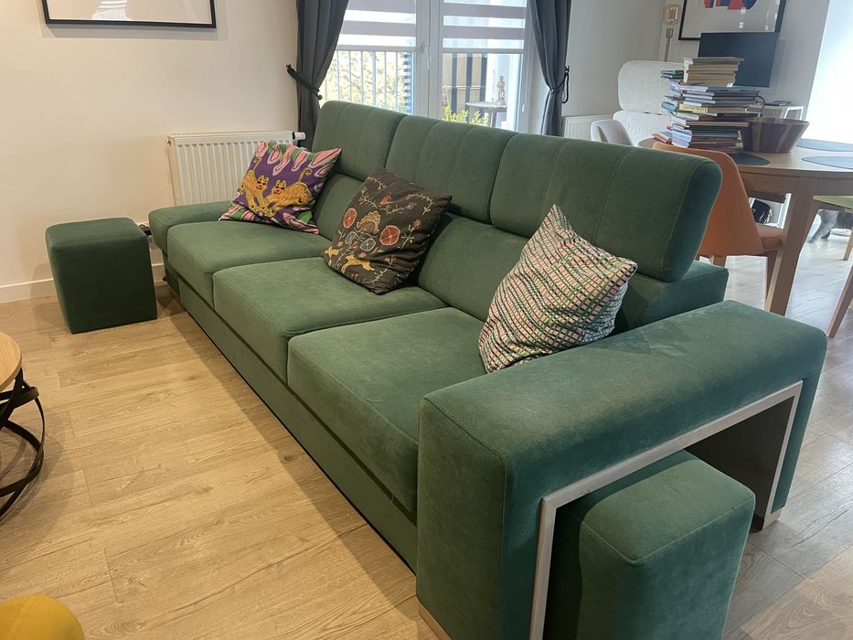 Zielona butelkowa sofa z funkcja spania z pufami i drewnianymi półkami