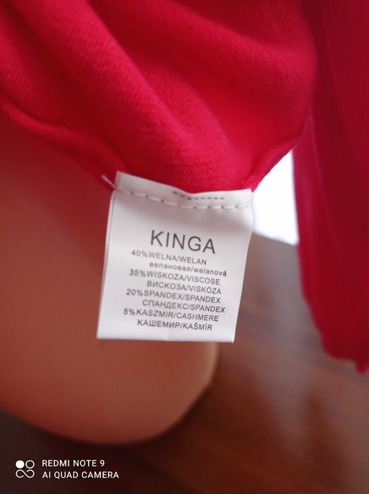 Duży ładny czerwony, damski sweterek z ozdobnym zapięciem.