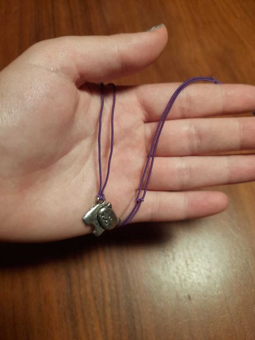 Fio rôxo com pendente prateado em forma de gatinho. 3,50 eur