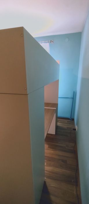 Łóżko antresola z biurkiem i szafką oraz szafą.