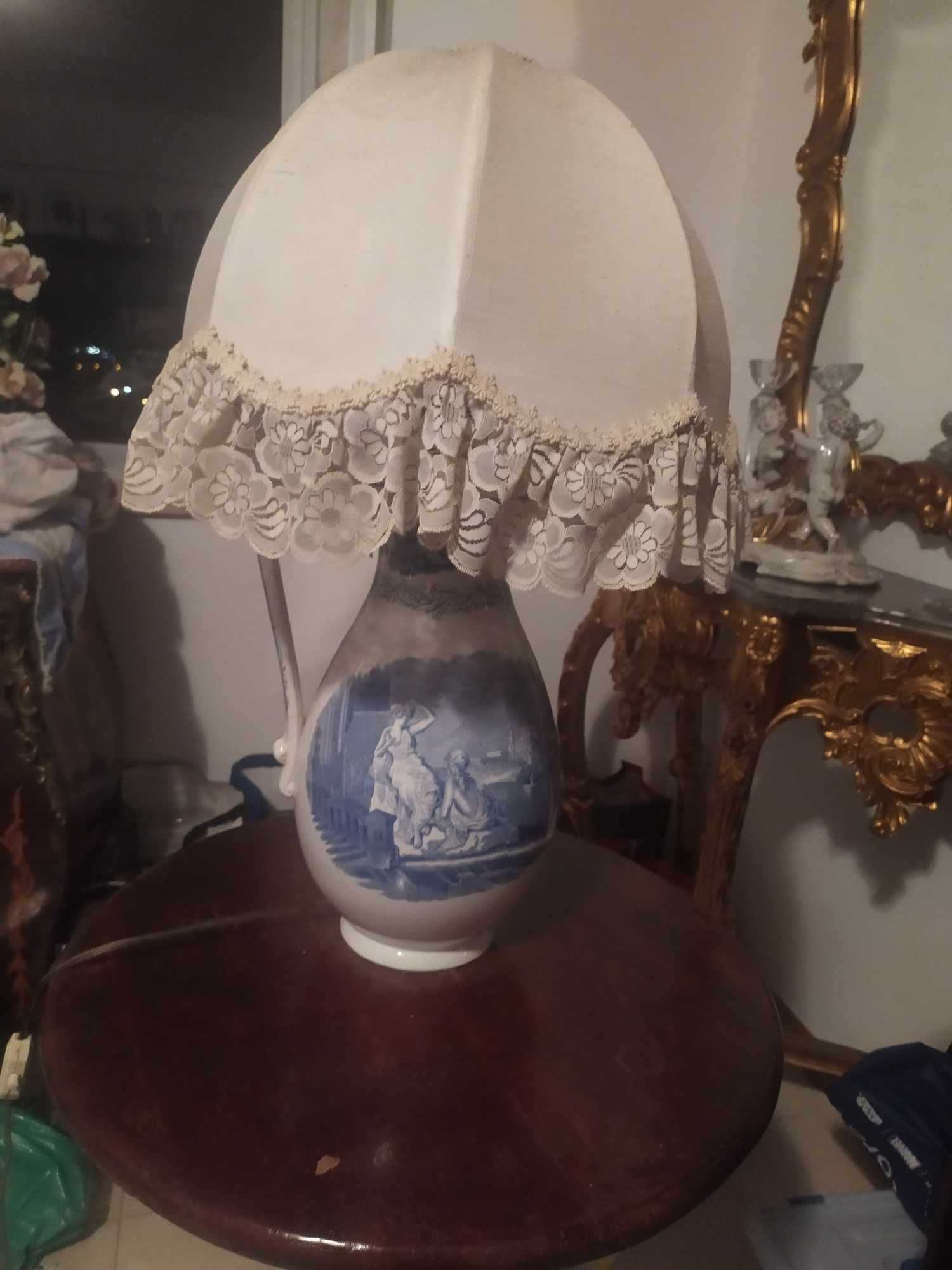 vende-se candeeiro em forma de urna  com motivo mitológico numa mesa