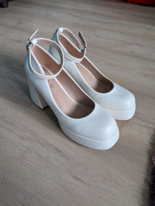 Білі туфлі на високому каблуку.