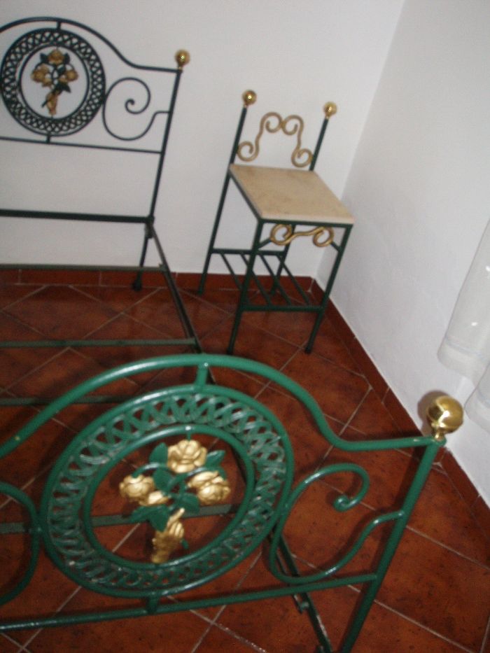 cama de ferro com mesa de cabeceira e candiero de teto
