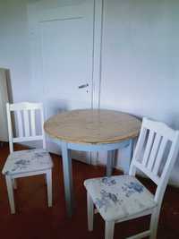Drewniany okrągły stół z dwoma krzesłami.