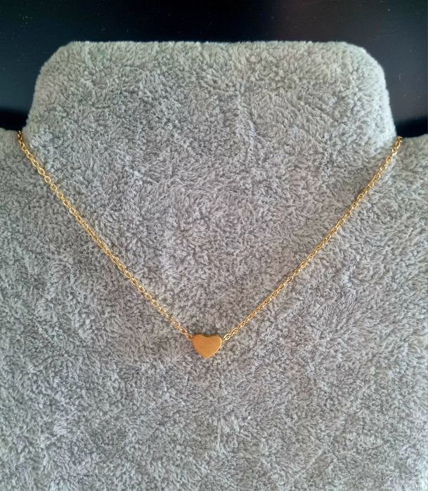 Colar dourado, em aço, com pequeno coração fixo. Tem extensor