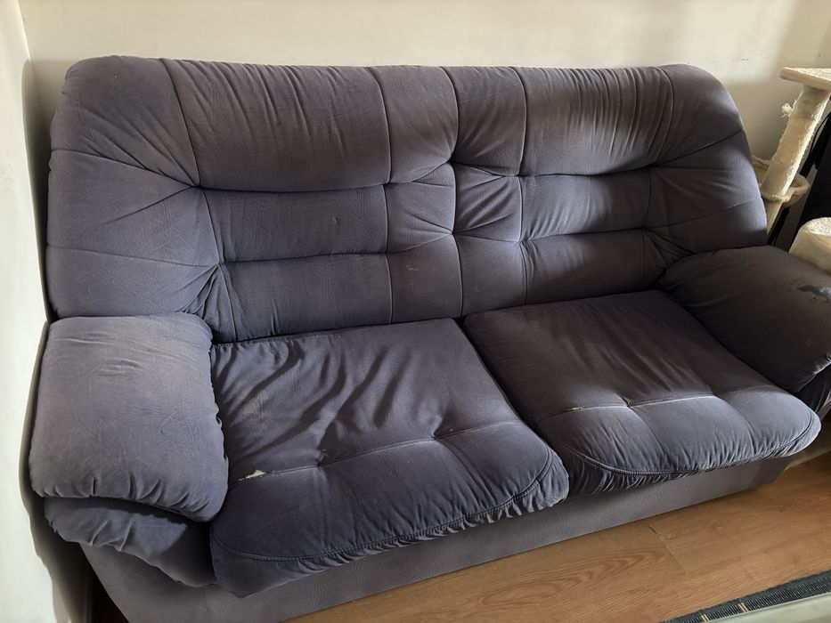 Sofá de sala, azul, com alguns anos e marcas de uso.