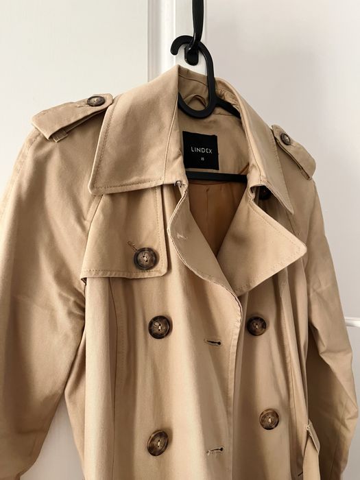 Beżowy płaszcz, trencz dwurzędowy z paskiem, taliowany