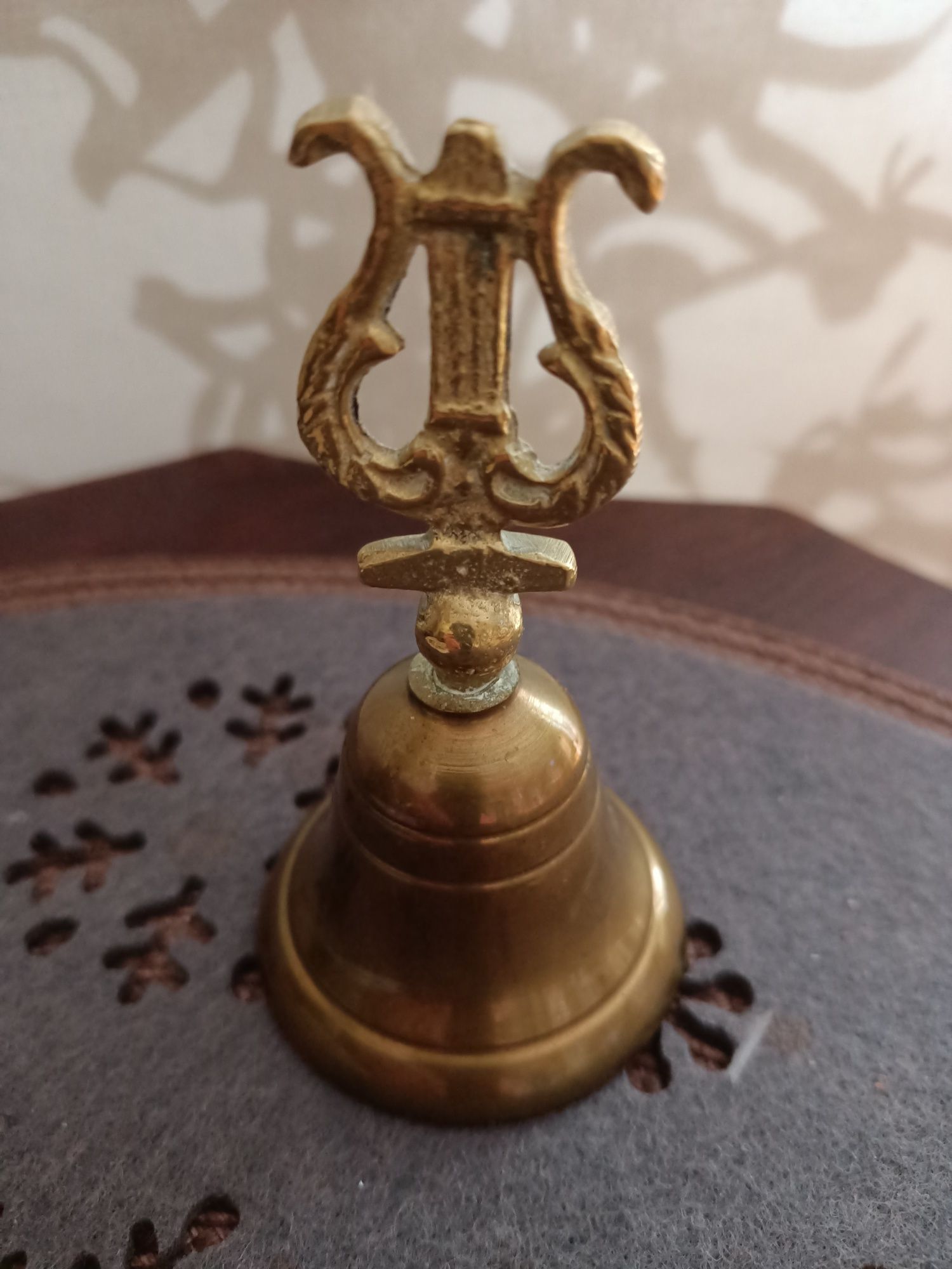 Zabytkowy dzwonek mosiężny figuralny z lirą.