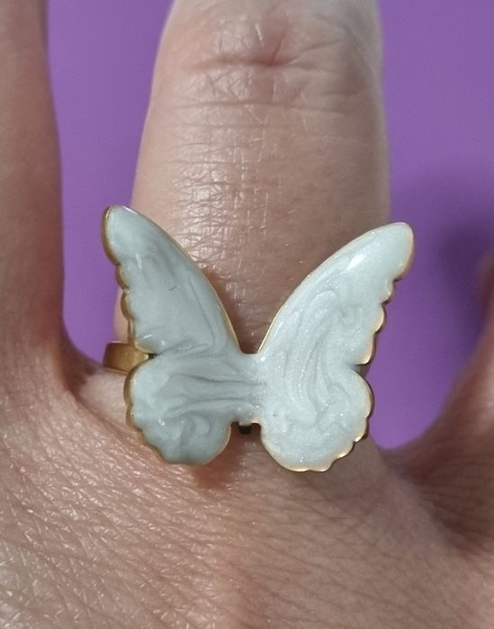 Anel dourado, em açol, com borboleta branca esmaltada. Ajustável