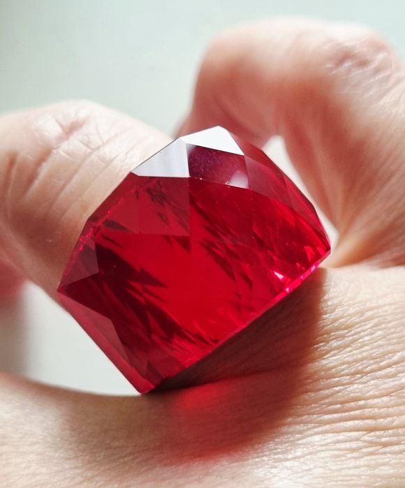 Anel dourado, em aço, com vermelho facetado na parte de cima. T17