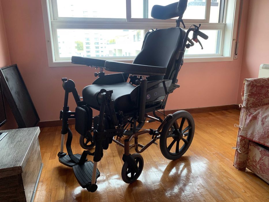 Cadeira de rodas com inclinação no encosto e com apoio de cabeça.
