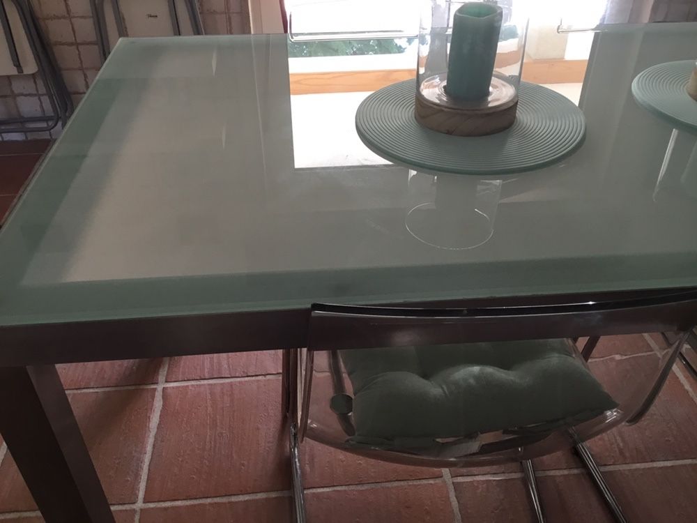 Mesa com estrutura em inox e tampo de vidro e 4 cadeiras em acrilico