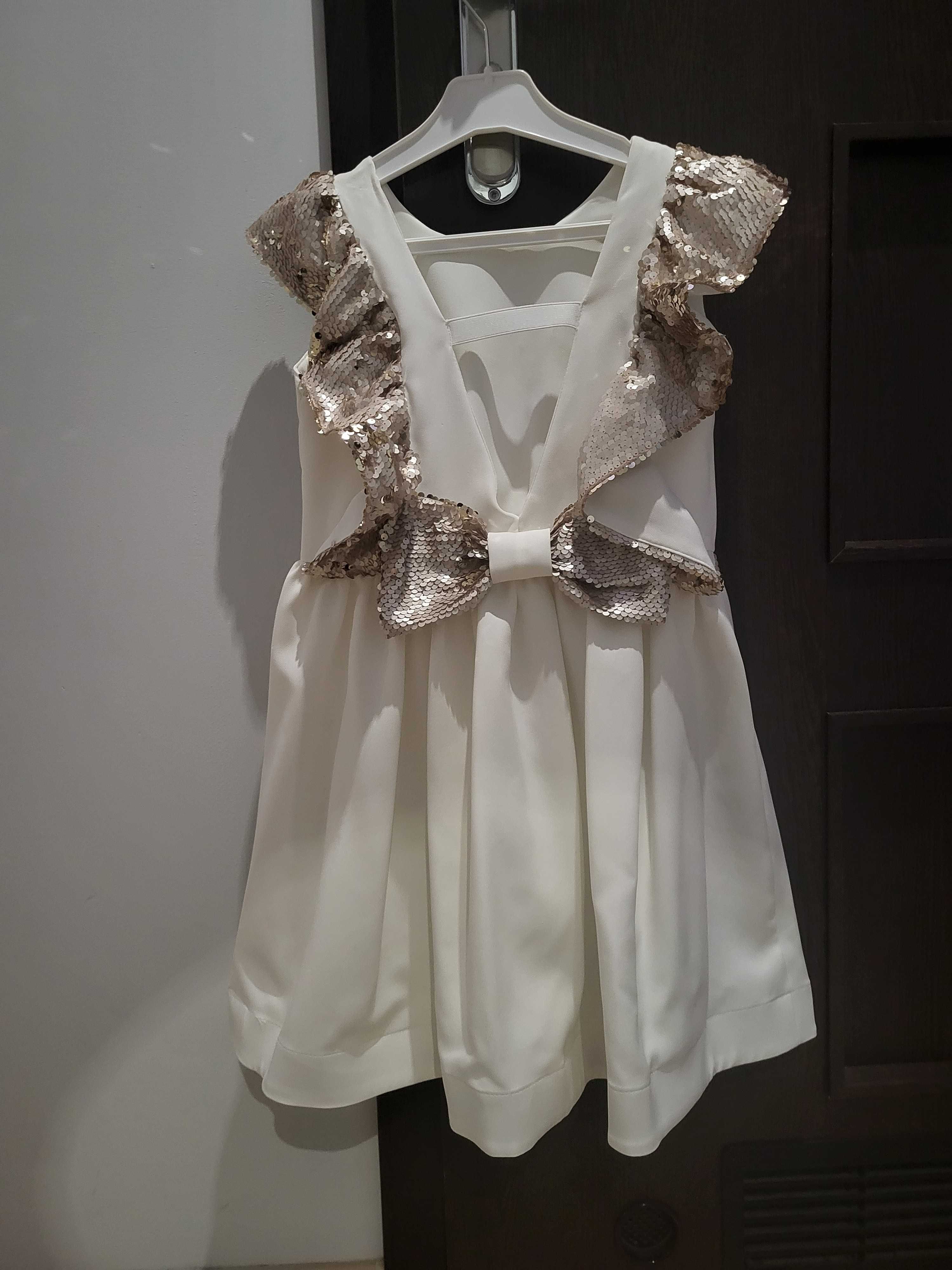 Prześliczna sukienka biała z cekinami i kokardką stan idealny r. 134