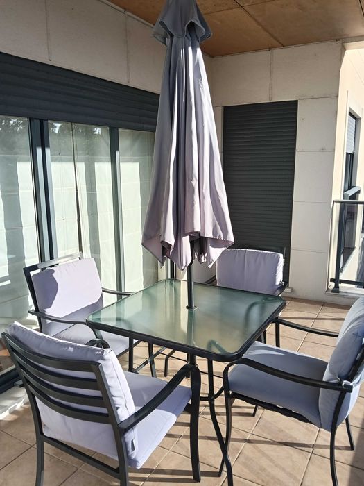 Mesa jardim com quatro cadeiras e chapéu sol