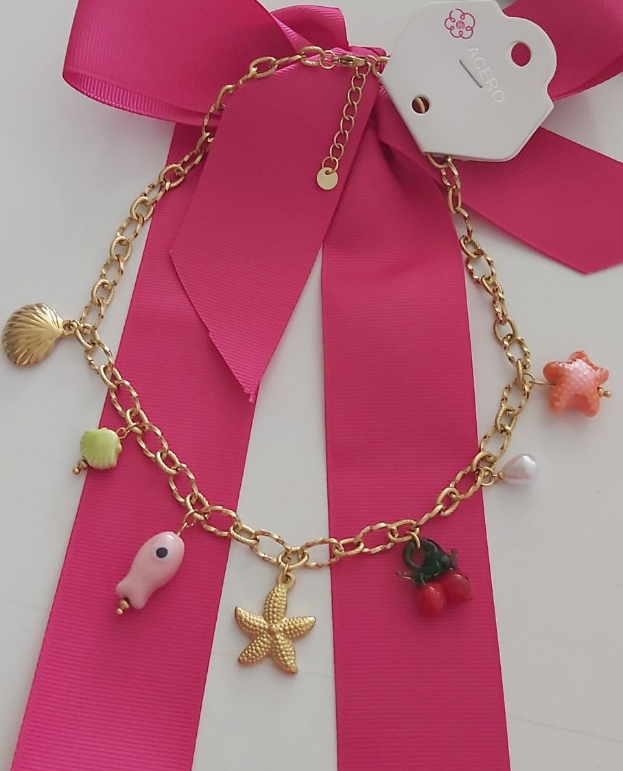Colar dourado, em aço, com 7 pingentes diferentes. Tem extensor
