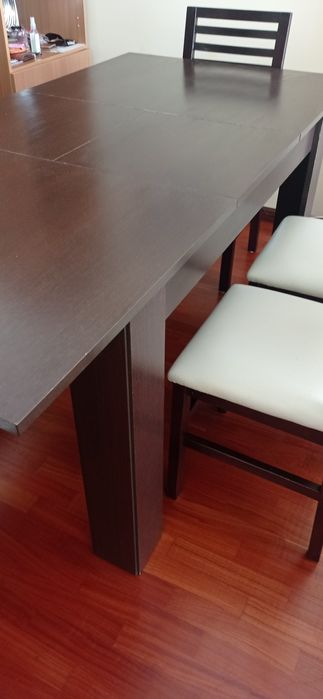 Mesa de madeira castanho escuro com seis cadeiras de pele
