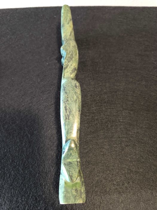 Escultura de mulher em pedra de cor verde.