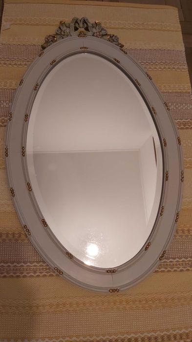 Espelho biselado com moldura de madeira com detalhes esculpidos.