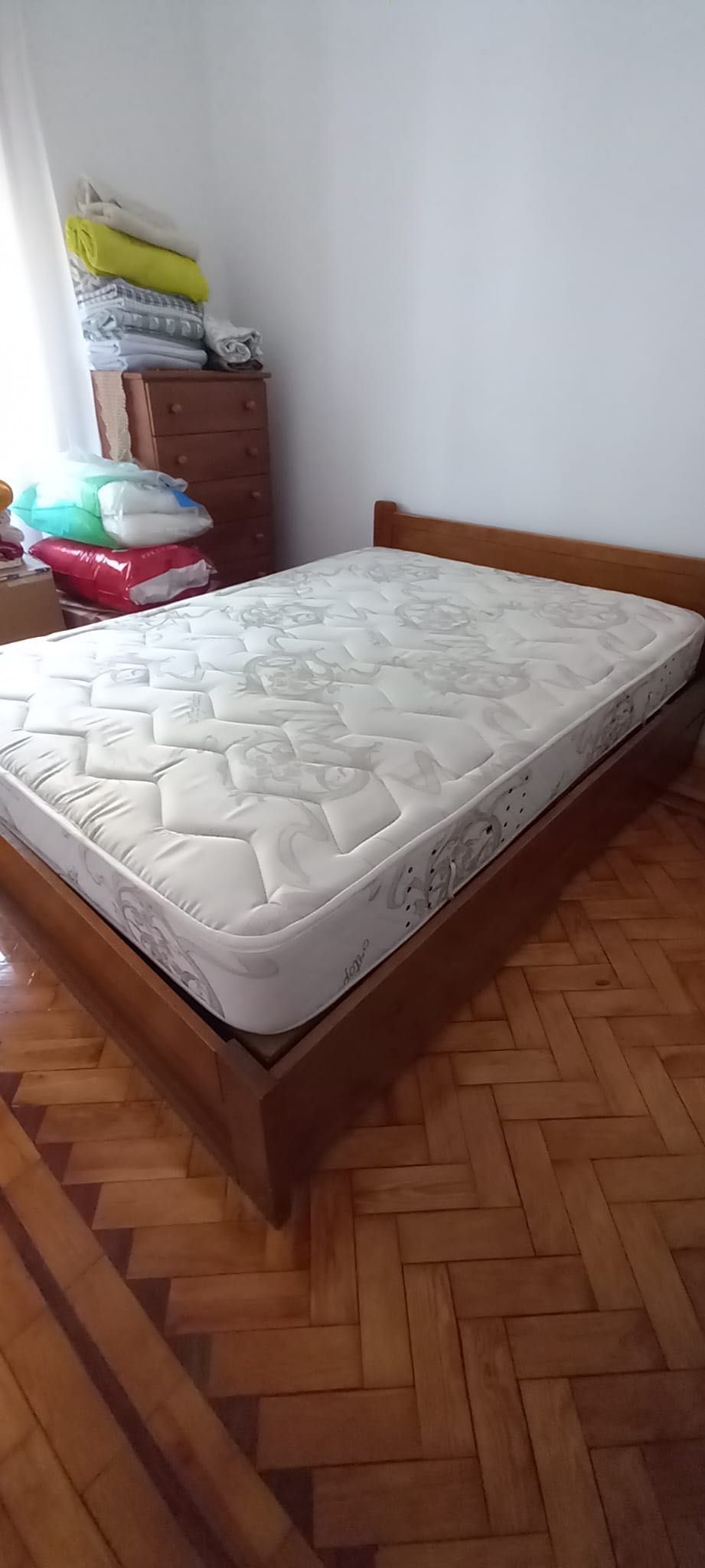 Cama de casal de madeira com colchão e mesa de cabeceira
