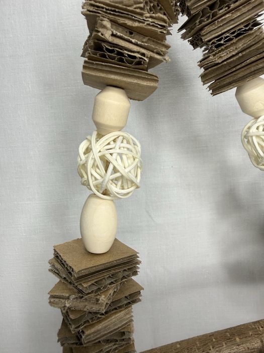 Mała huśtawka dla ptaków z tekturą i kulami wiklinowymi.