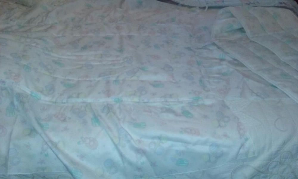 Colcha de cama de bebé com folhos aos lados e nos pés.