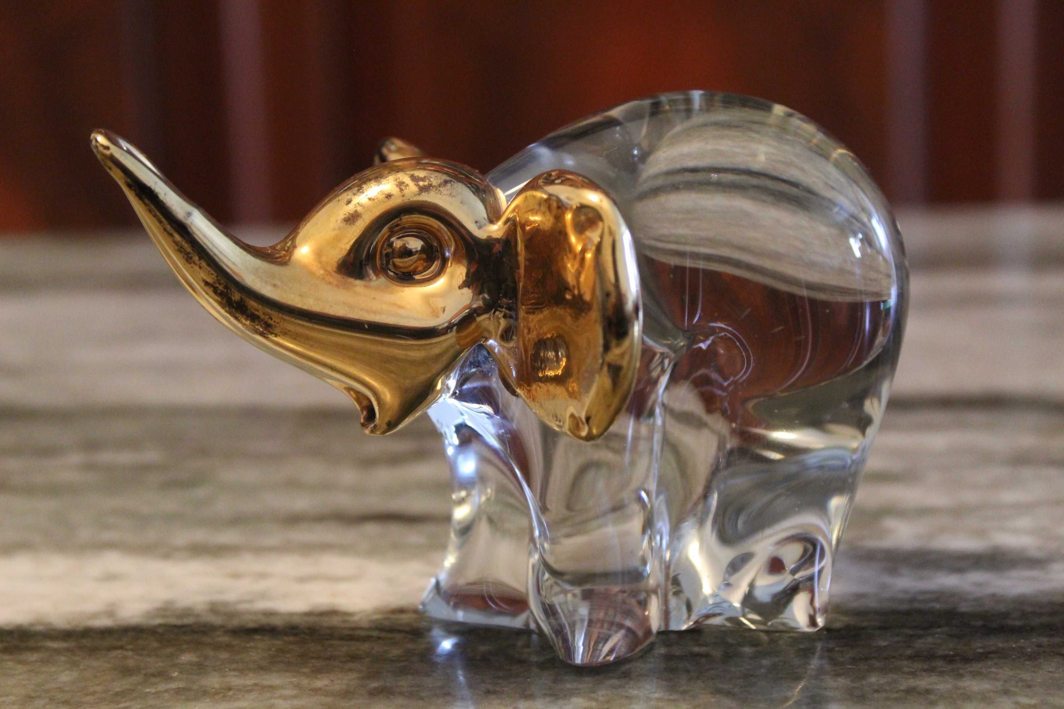 Estatueta de elefante em vidro transparente com detalhes em dourado.