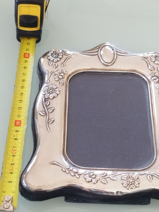 Moldura delicada com detalhes florais em relevo.

- Material: Prata
-