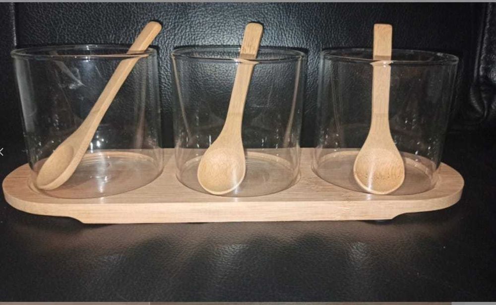 Trzy szklane pojemniczki z łyżeczkami na
bambusowej deseczce.