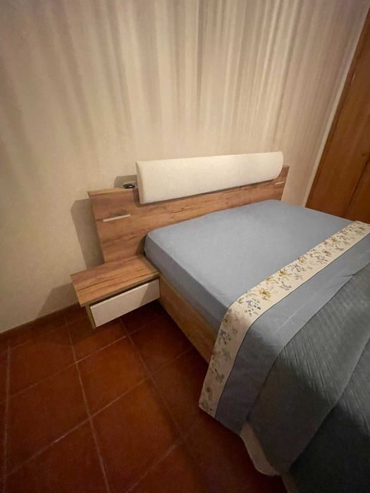 Cama de casal com mesas de cabeceira e iluminação