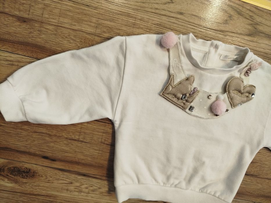 Biała bluza bawełna 80 86 z ozdobną odpinaną dekoracja na dekolcie.